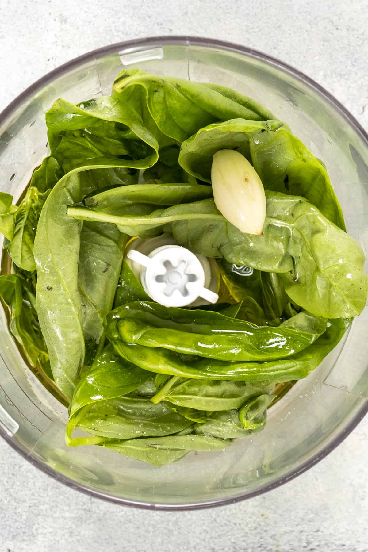 Basil leaves, garlic and olive oil in a food processor.