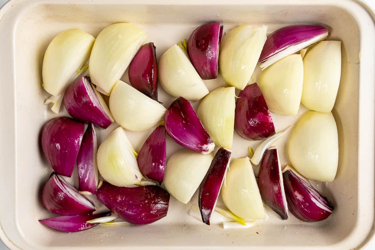 Red and white onion wedges in a white baking dish.