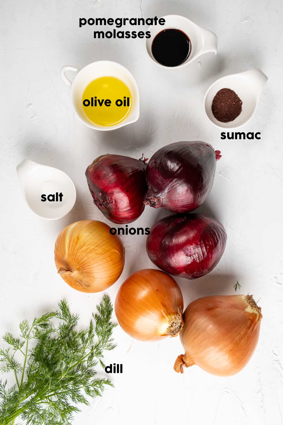 Red onions, brown onions, fresh dill, olive oil, pomegranate molasses, sumac and salt on a light background.