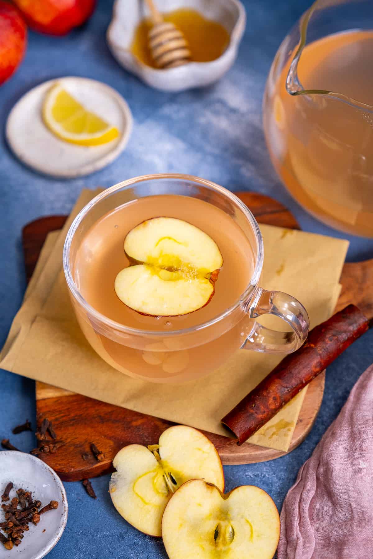 Apple tea in a glass cup, a cinnamon stick on the side.