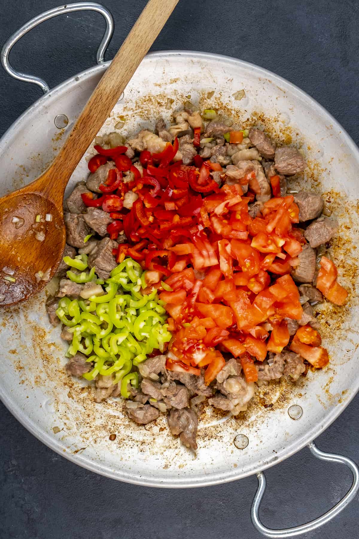 Chopped tomatoes and peppers thrown on cooked diced lamb in a traditional pan.