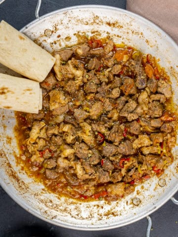 Turkish kavurma in a traditional pan and lavash bread on the side.