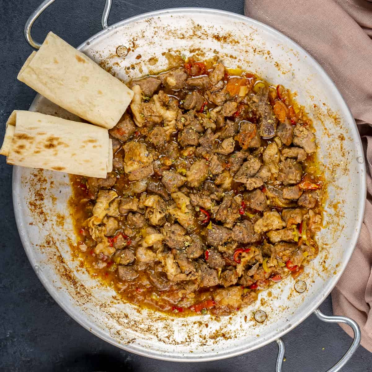 Turkish kavurma in a traditional pan and lavash bread on the side.