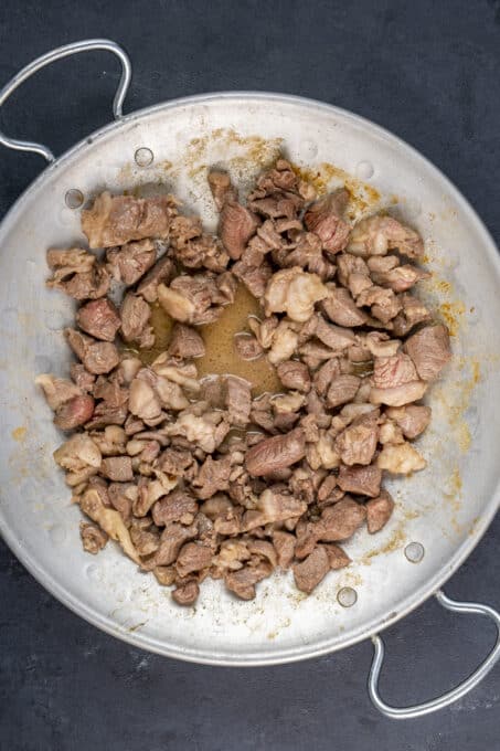 Diced lamb cooking in a traditional pan.