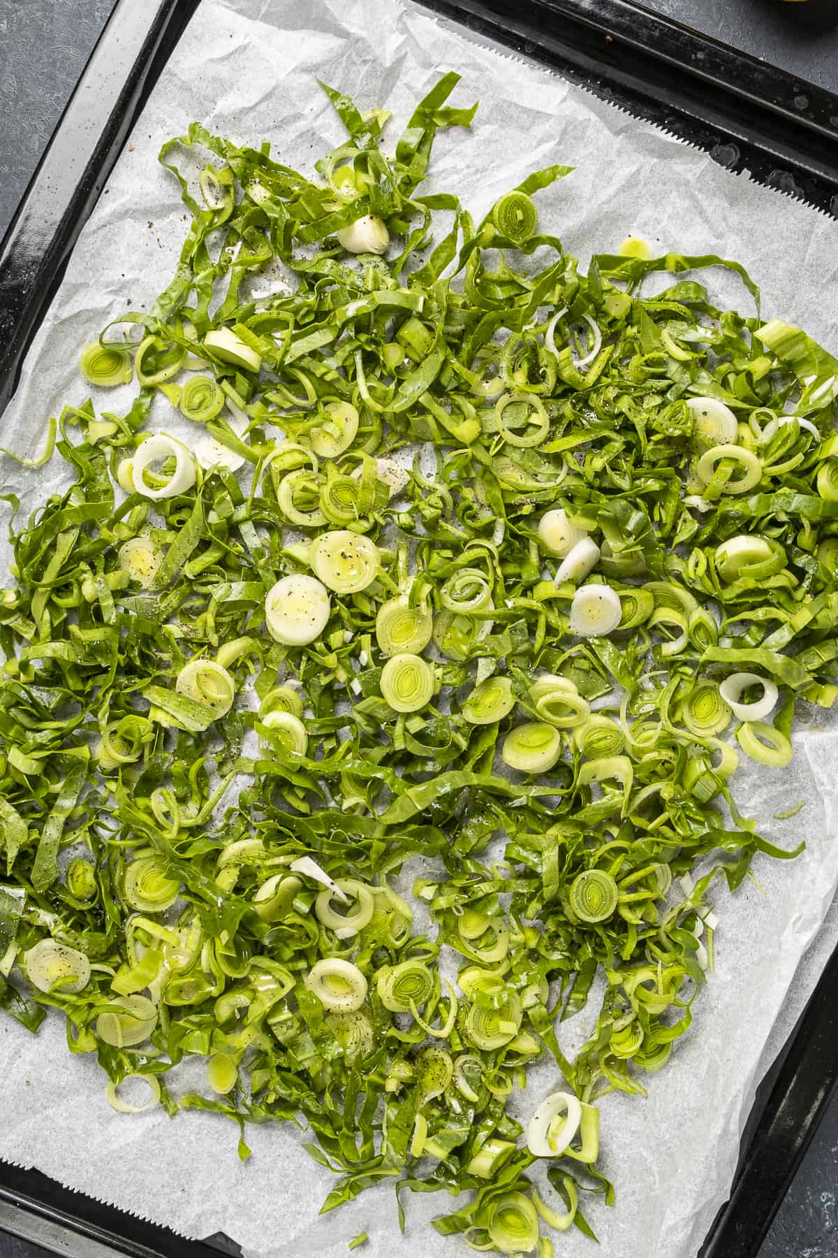 Chopped leeks and chard leaves in a baking tray.