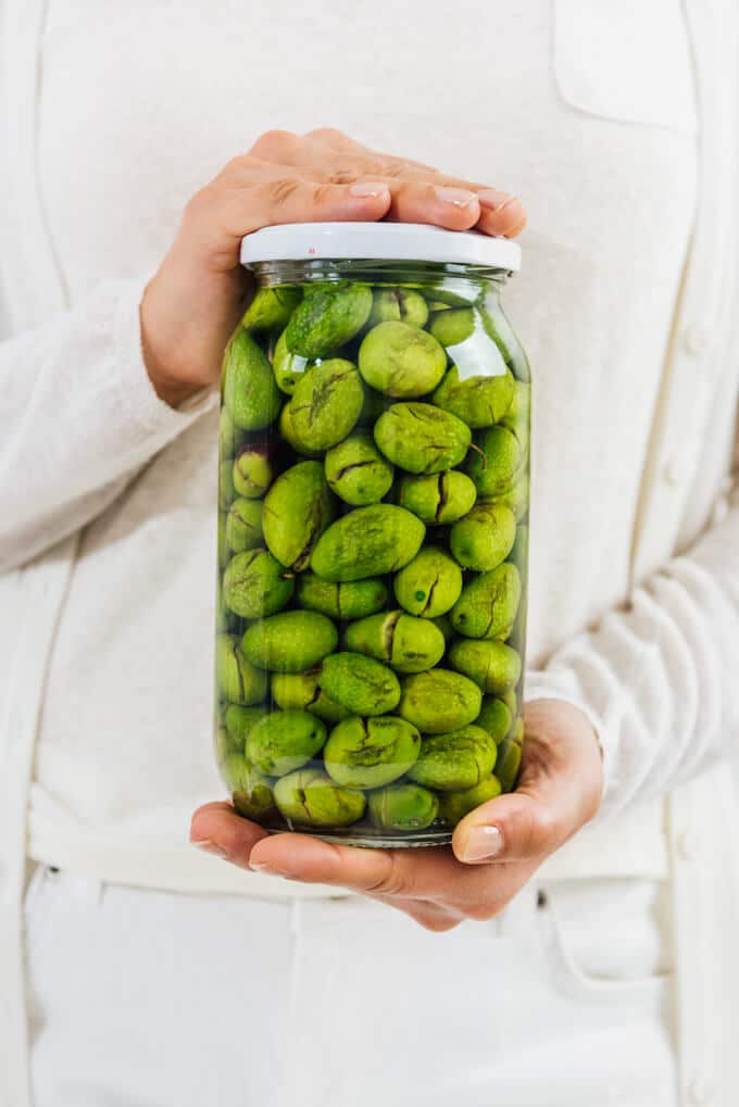 woman holding a jar of pickled green olives