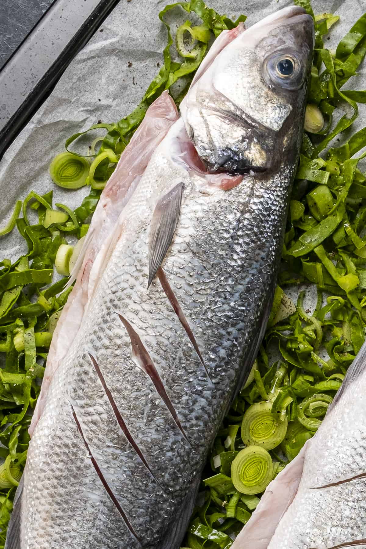 Fresh whole sea bass on chopped green vegetables.