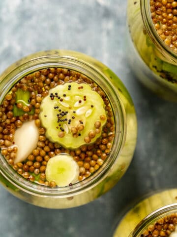 Armenian cucumber pickles with mustard seeds and coriander seeds in jars.