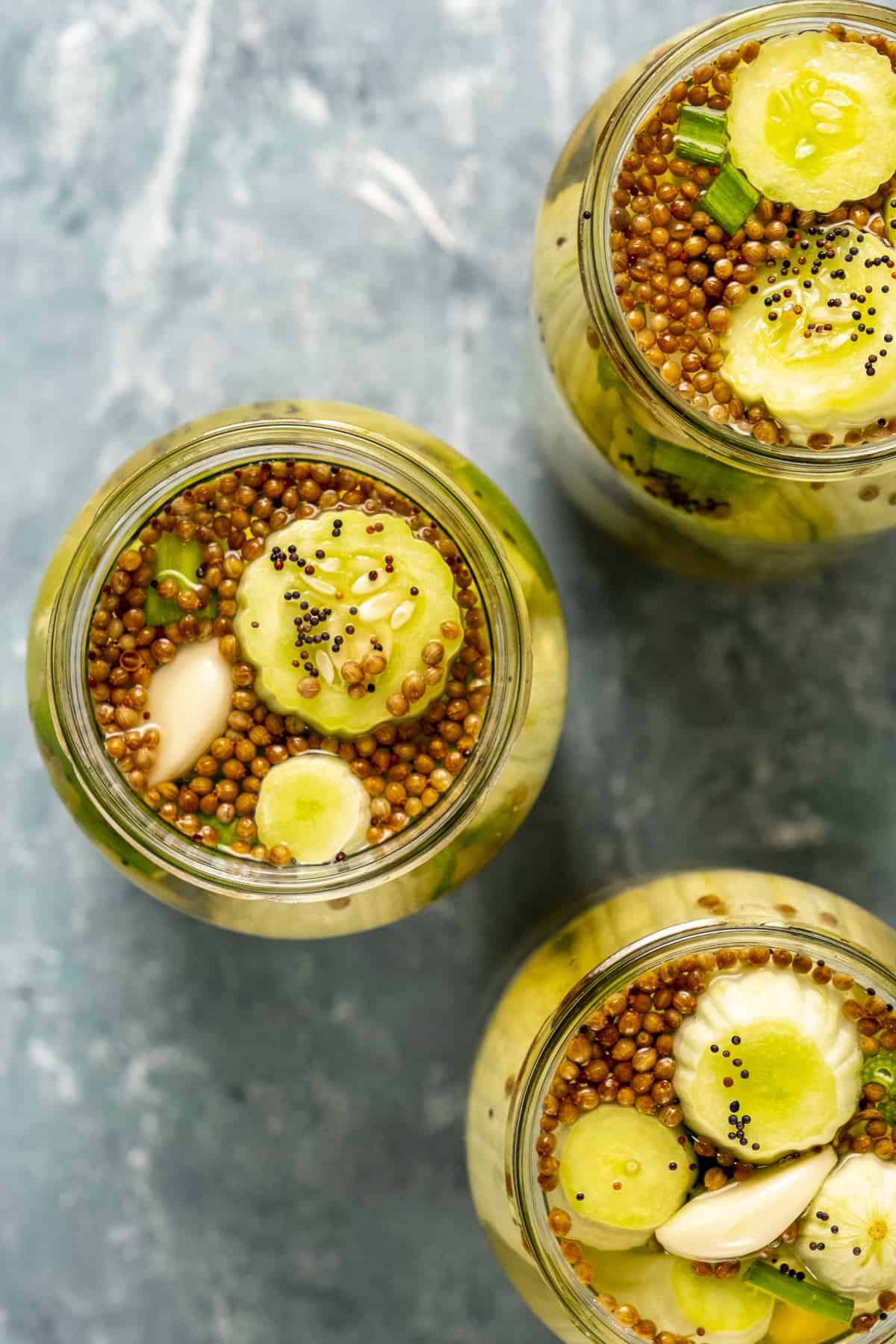 Armenian cucumber pickles with mustard seeds and coriander seeds in jars.