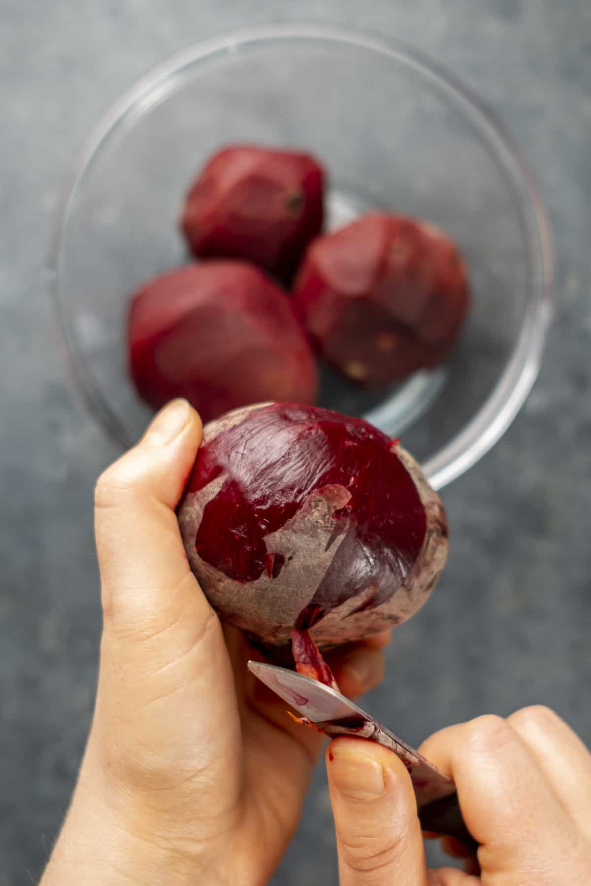 Hands peeling beets with a knife.