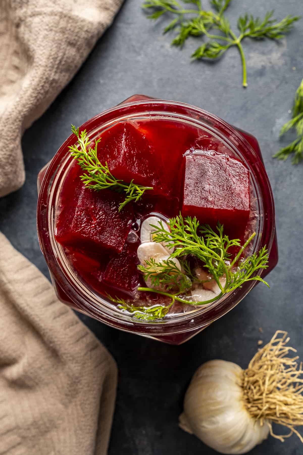 Pickled beets in a jar and garlic on the side.