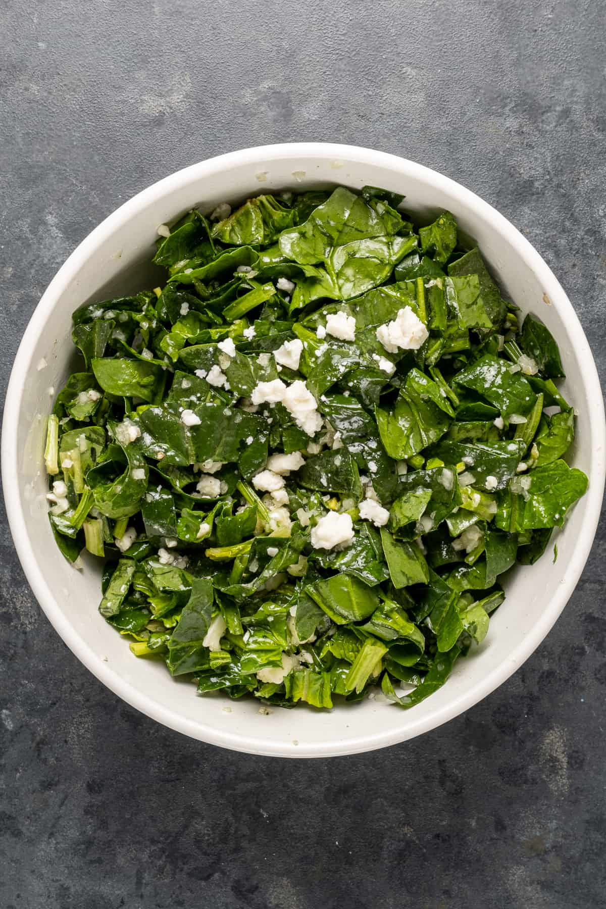 Spinach and cheese filling mixture in a white bowl