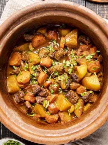 Beef casserole with potatoes and carrots in a clay pot.