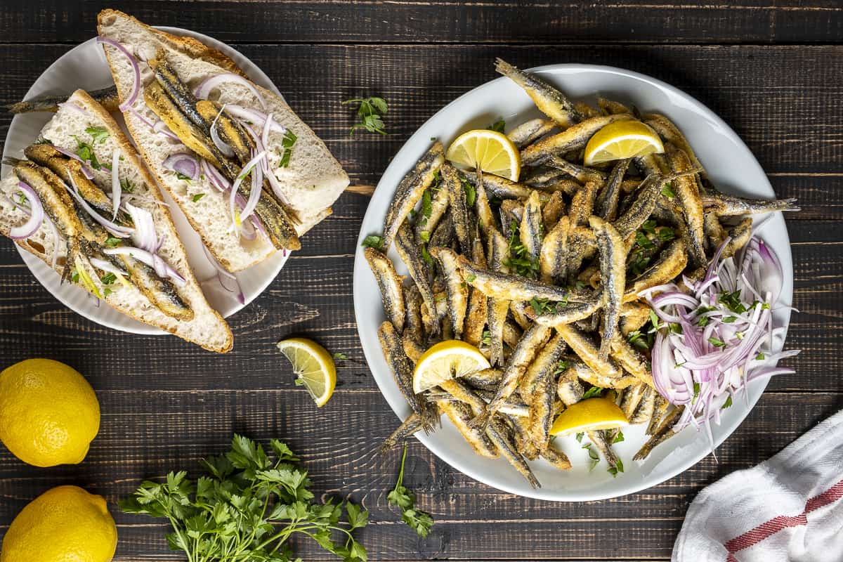 Fried hamsi served on a plate and in sandwich breads.