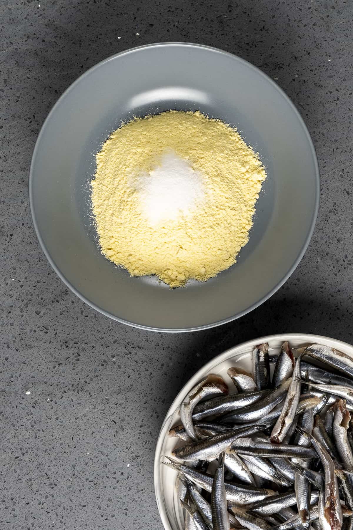 Hamsi fish in a bowl and cornmeal with salt in another bowl.