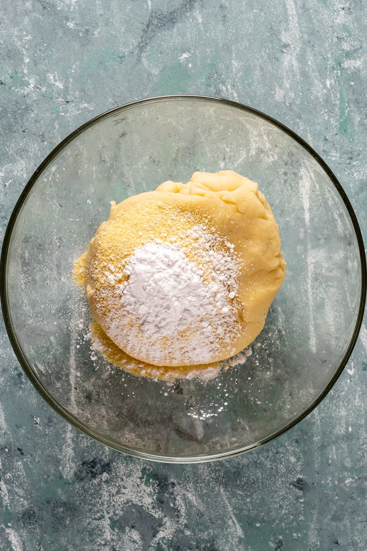 Tulumba dessert dough topped with cornstarch in a glass mixing bowl.