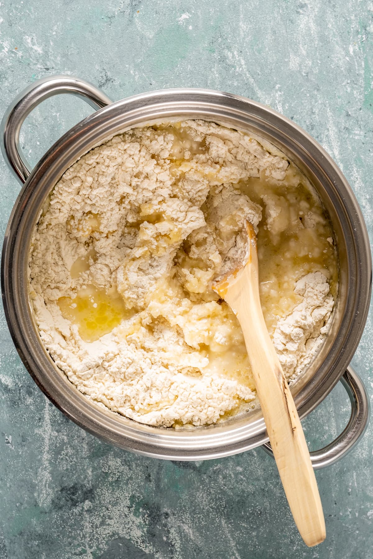 Flour, melted butter and water in a pan with a wooden spoon inside it.
