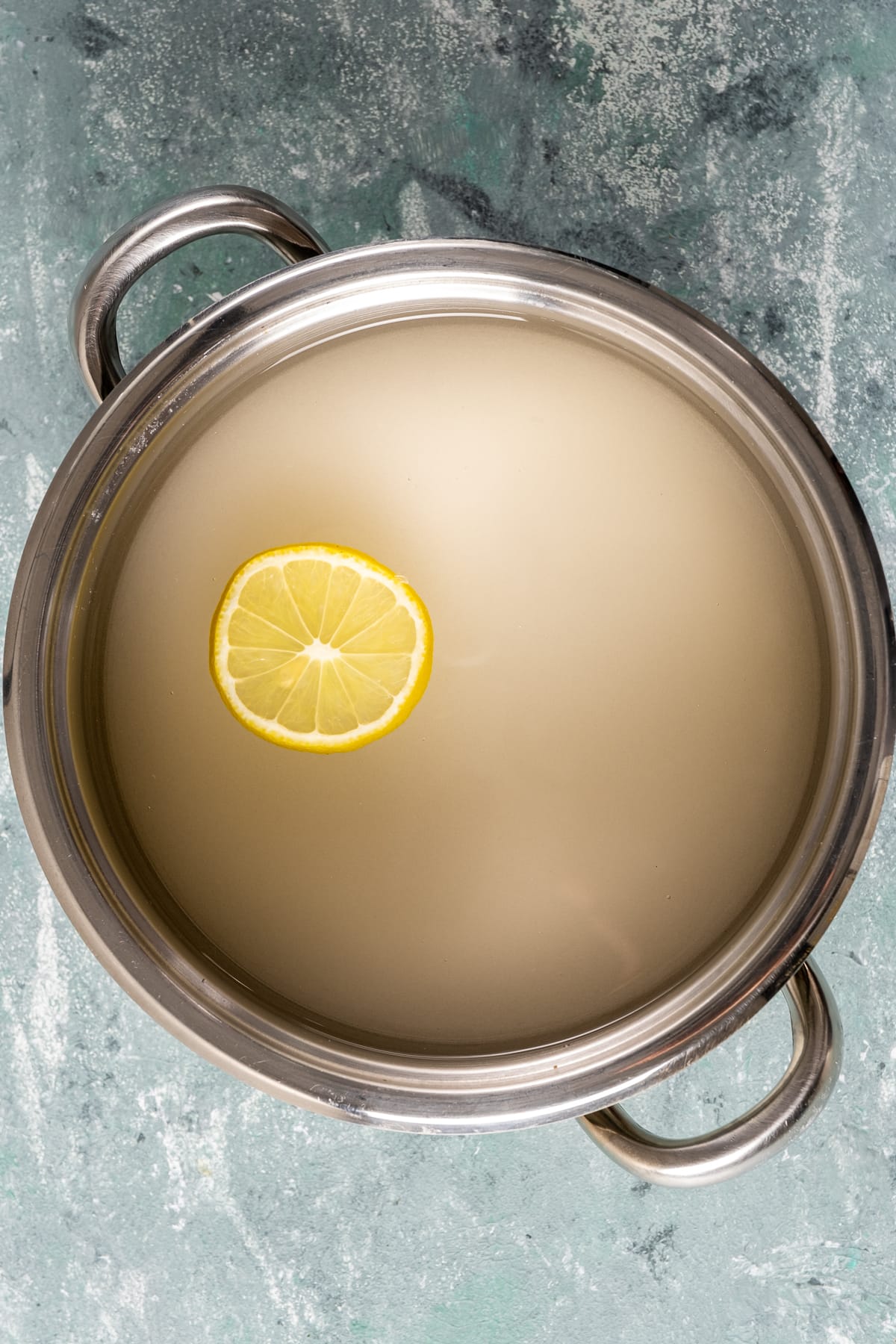 Lemon syrup with a lemon wedge in a pan.