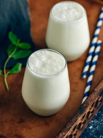 Two glasses of Turkish yogurt drink ayran photographed in a wooden tray.