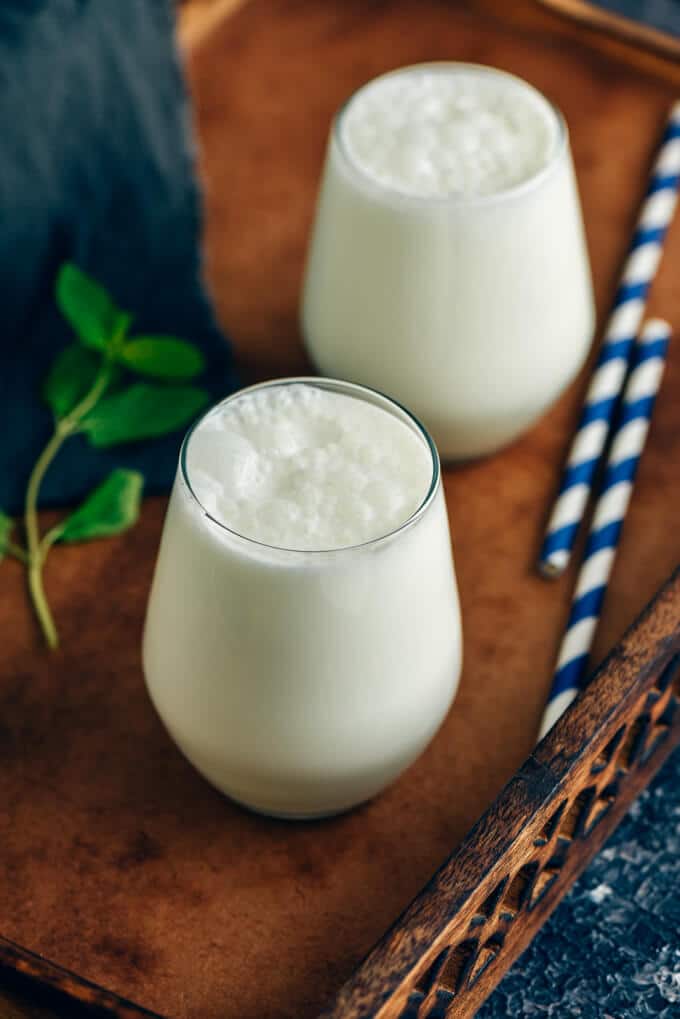 Two glasses of Turkish yogurt drink ayran photographed in a wooden tray.