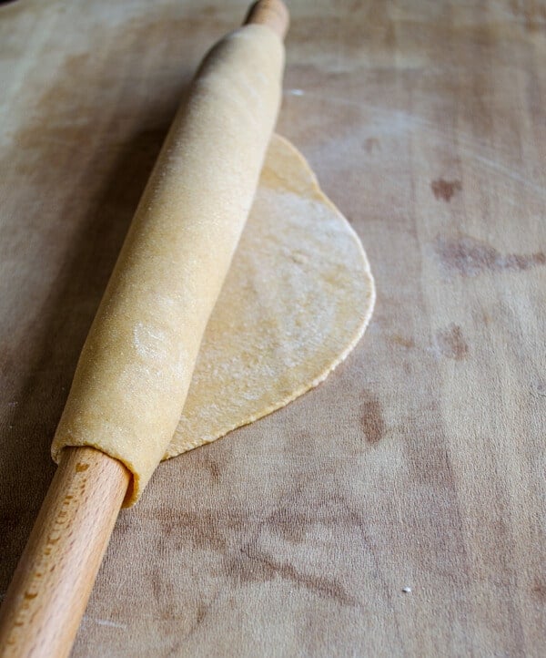 Rolled out dough wrapped on a thin rolling pin on a wooden board.