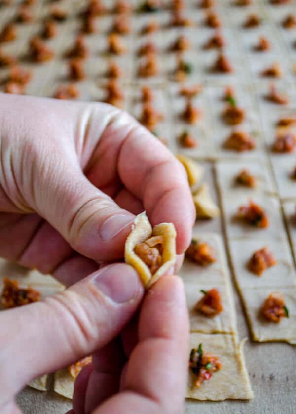 Hands closing manti dough squares.