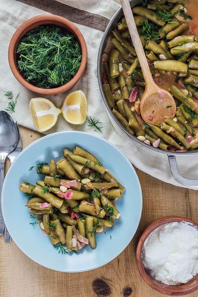 Fresh Fava Beans are braised in olive oil with tomatoes and onions and served at room temperature with lemon and yogurt. This is my favorite meatless dinner in spring.