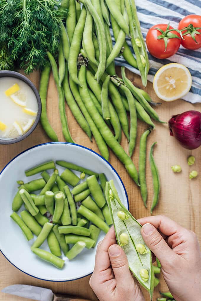 Fresh Fava Beans are braised in olive oil with tomatoes and onions and served at room temperature with lemon and yogurt. This is my favorite meatless dinner in spring.