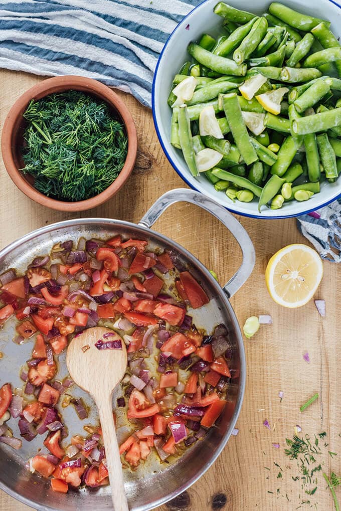 Fresh Fava Beans are braised in olive oil with tomatoes and onions and served at room temperature with lemon and yogurt. This is my favorite meatless dinner in spring.