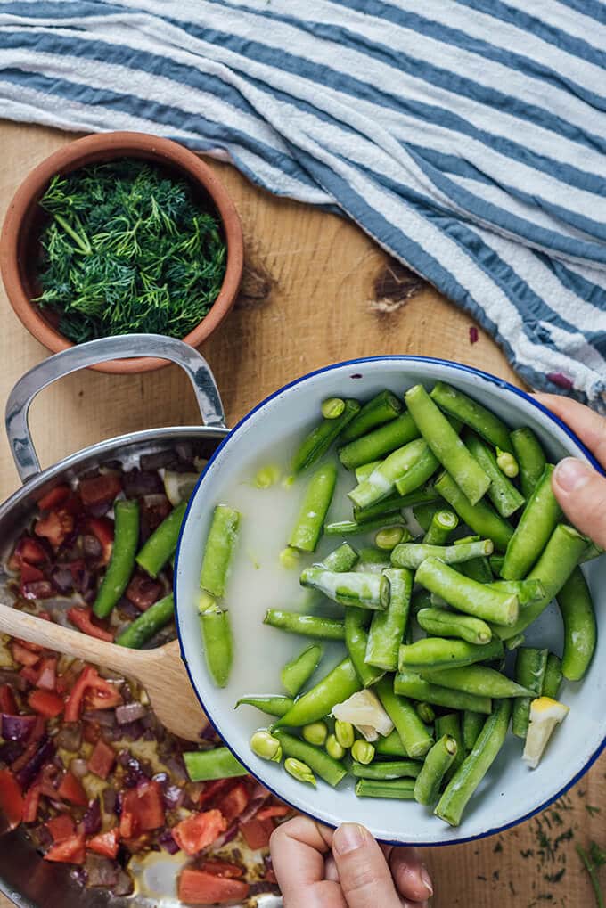 Fresh Fava Beans are braised in olive oil with tomatoes and onions and served at room temperature with lemon and yogurt. This is my favorite meatless dinner in spring.