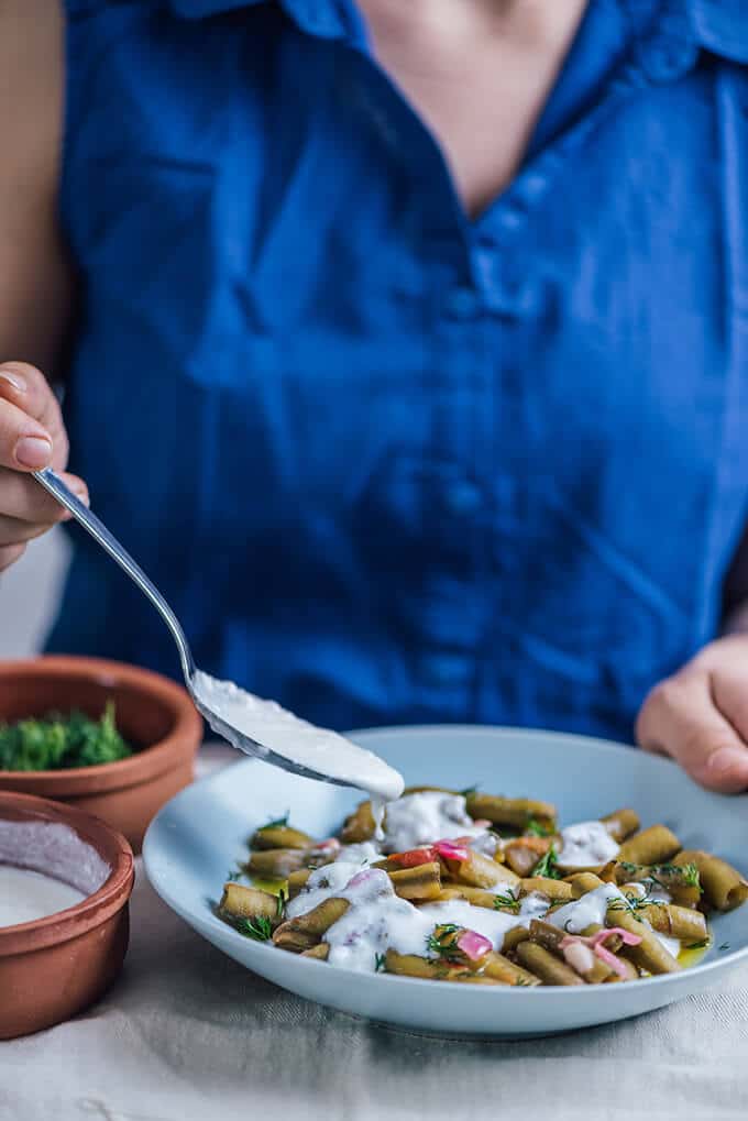 Fresh Fava Beans are braised in olive oil with tomatoes and onions and served at room temperature with lemon and yogurt. This is my favorite meatless dinner in spring.