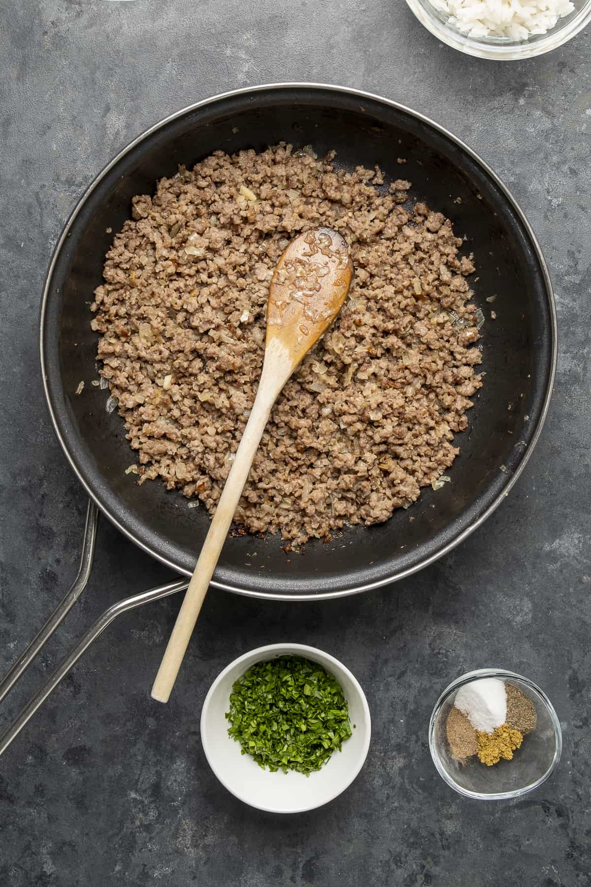Ground beef cooked in a non-stick pan and a wooden spoon inside it.