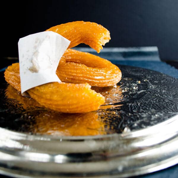 Half eaten Turkish churro on a metal plate.