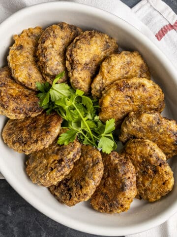 Kadinbudu kofte garnished with parsley in a white oval baking pan.