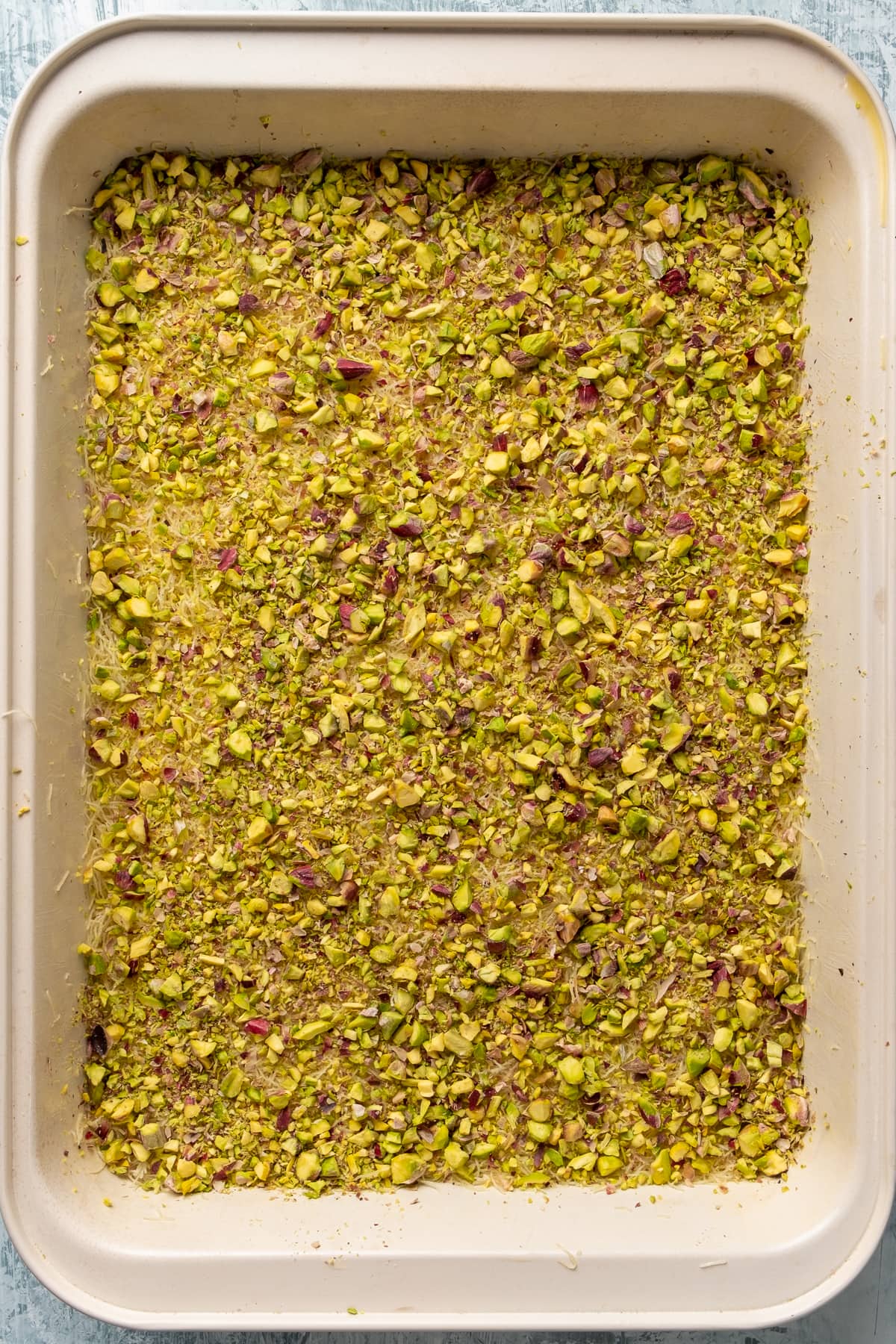 Shredded kadayif dough flattened and topped with a generous amount of crumbled pistachios.