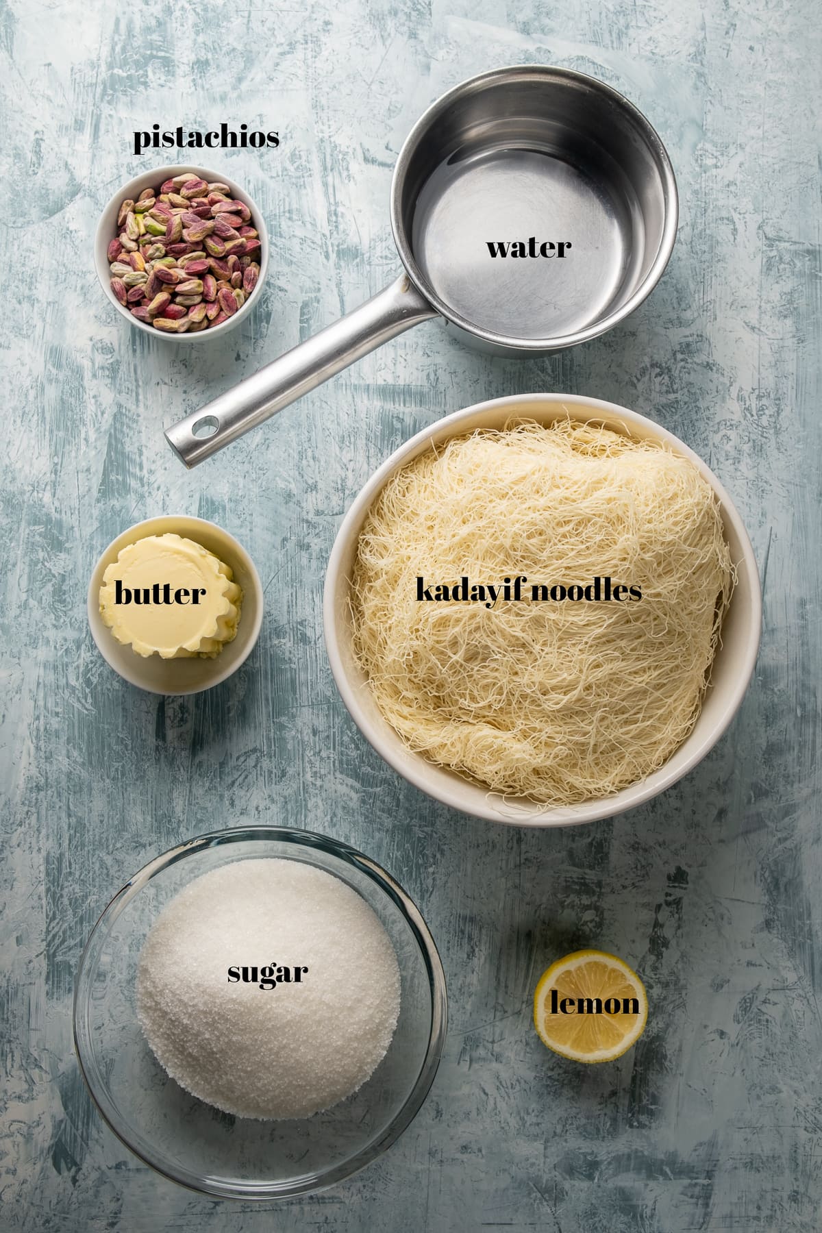 Turkish kadayif noodles, pistachios, water, butter, sugar in separate bowls and a slice of lemon on the side.