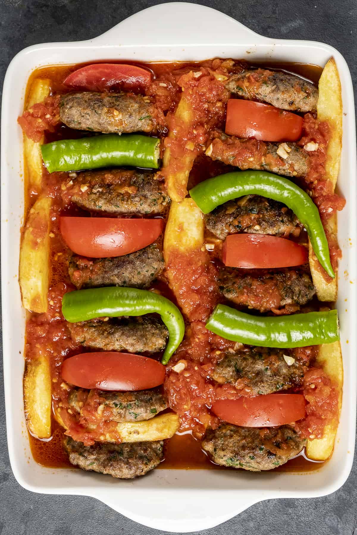 Meatballs, potatoes, tomatoes, green peppers all in a baking pan.