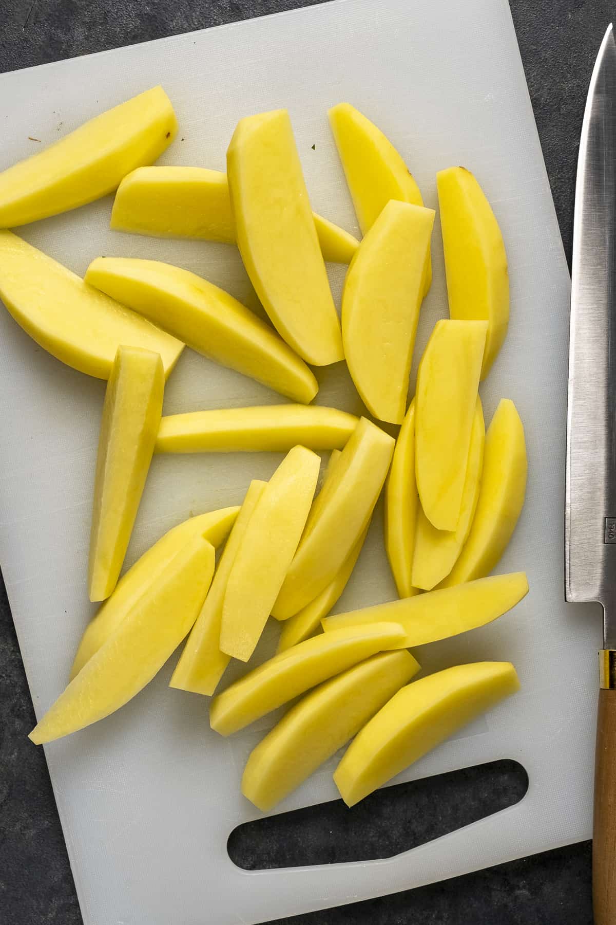 Thick potato slices on a cutting board.