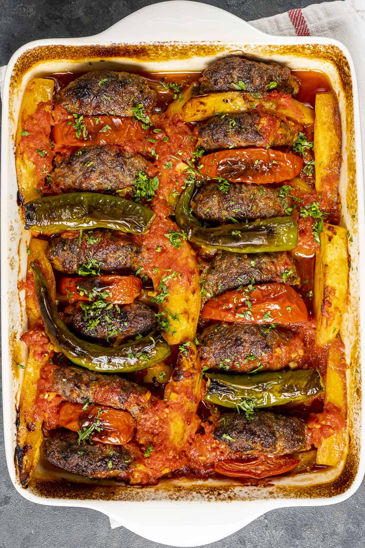 Baked meatballs and potatoes with tomato sauce in a baking pan.