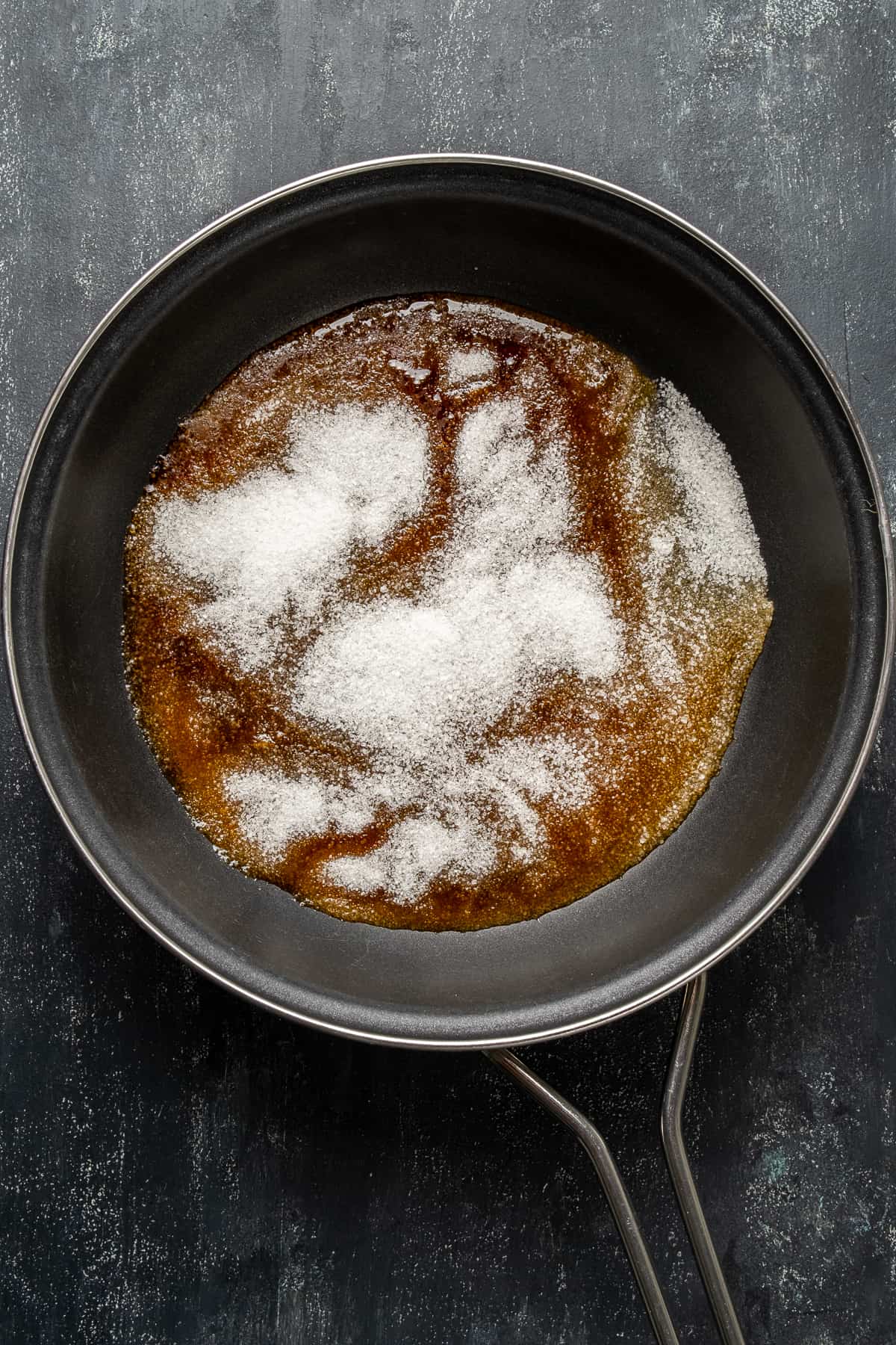 Granulated sugar half melted in a non stick pan.