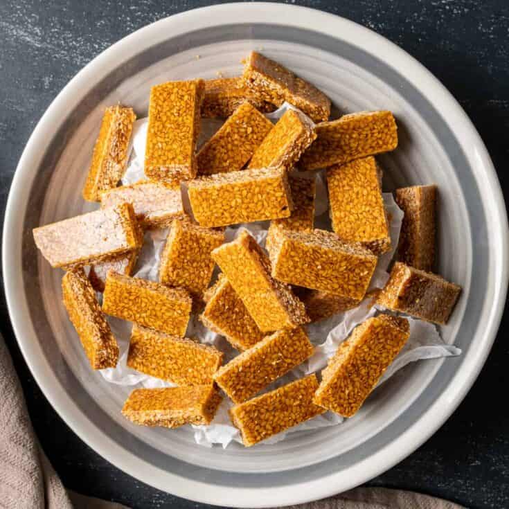 Sesame seed candies in small rectangular shape in a white bowl.