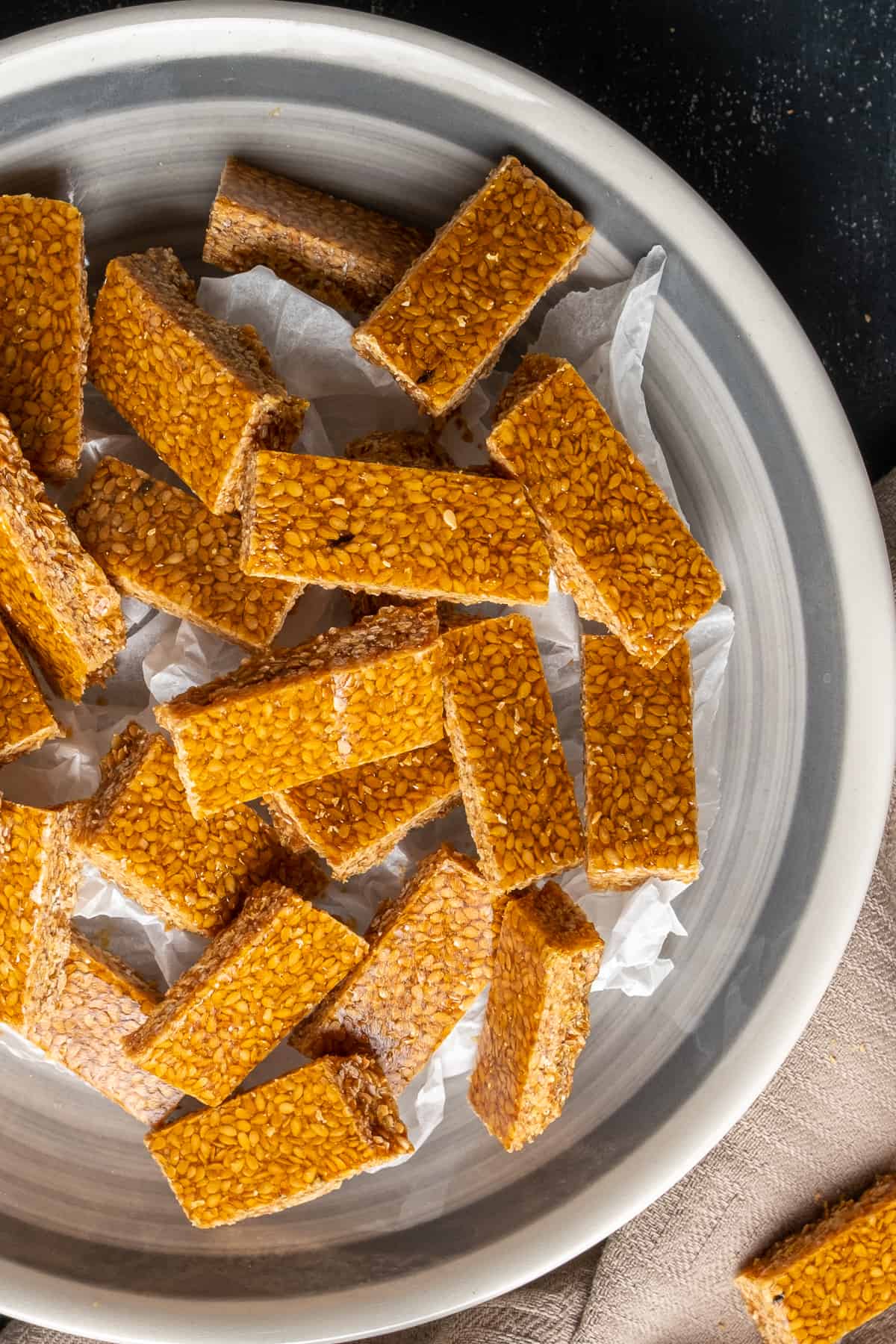 Sesame seed candies in small rectangular shape in a white bowl.