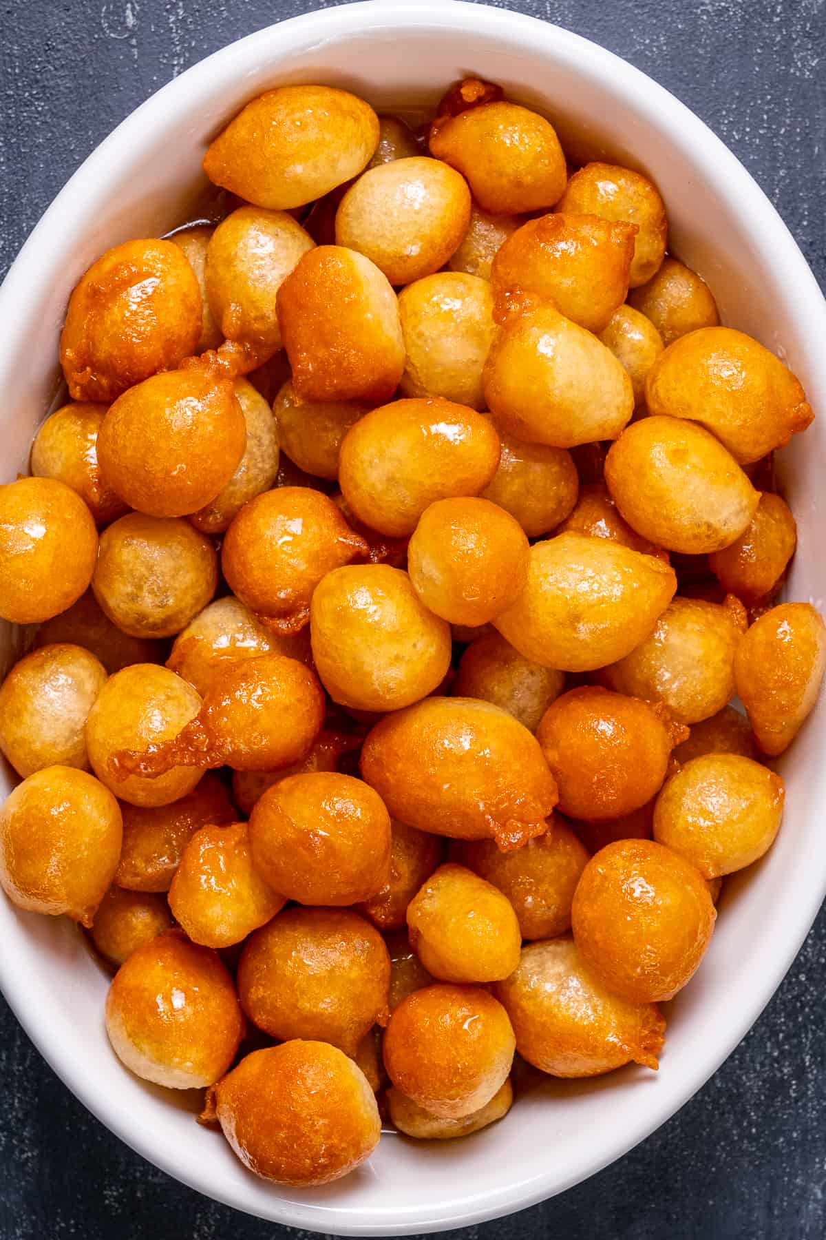 Fried dough balls in a white oval bowl.