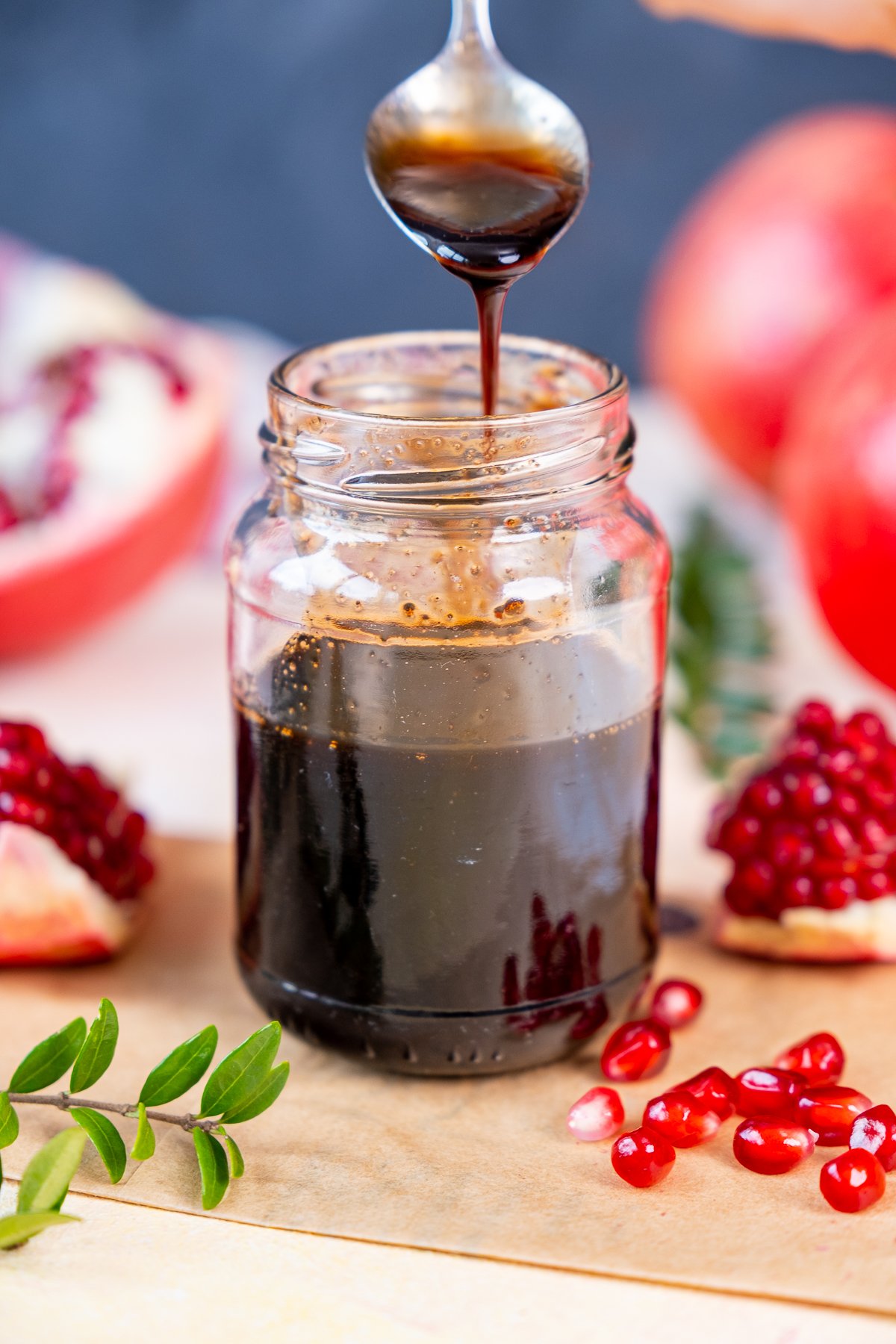 Pomegranate molasses in a jar and a spoon pouring into it.