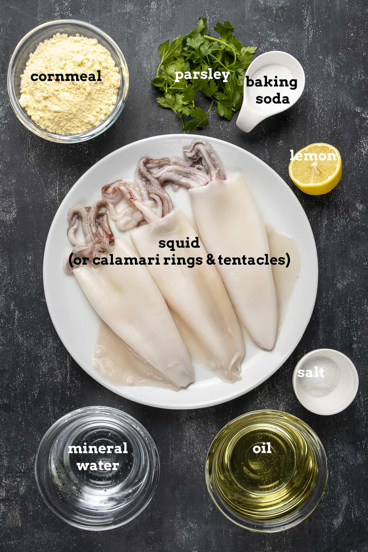 Whole squids, cornmeal, parsley, baking soda, lemon, salt, oil and mineral water on a dark background.