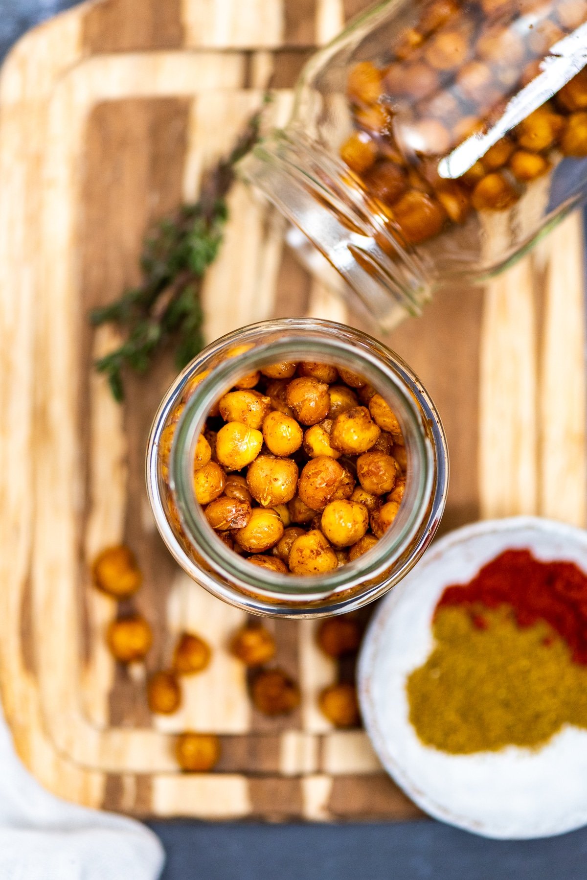 Crispy and spicy chickpeas are in two glass jars without a lid. Spices on the side.