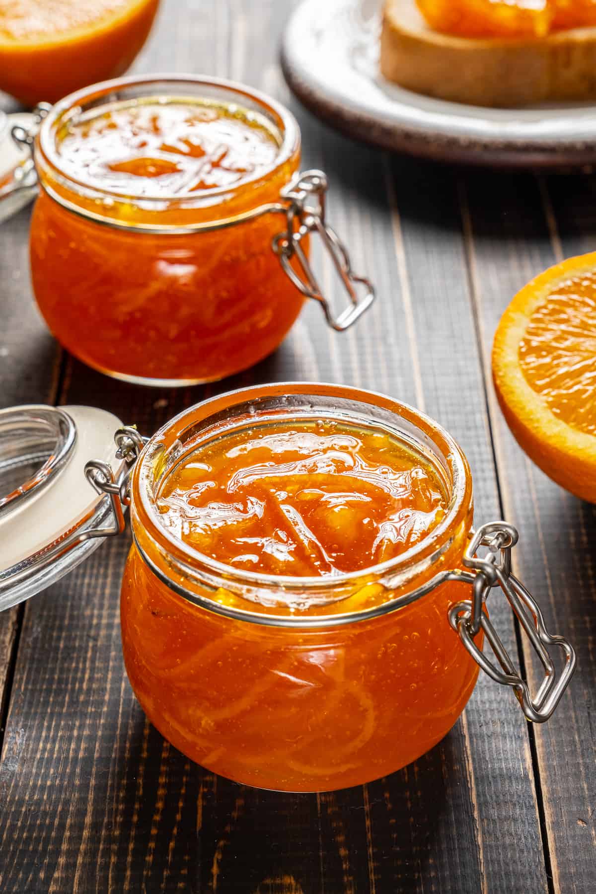 Orange marmalade in glass jars on a wooden background.