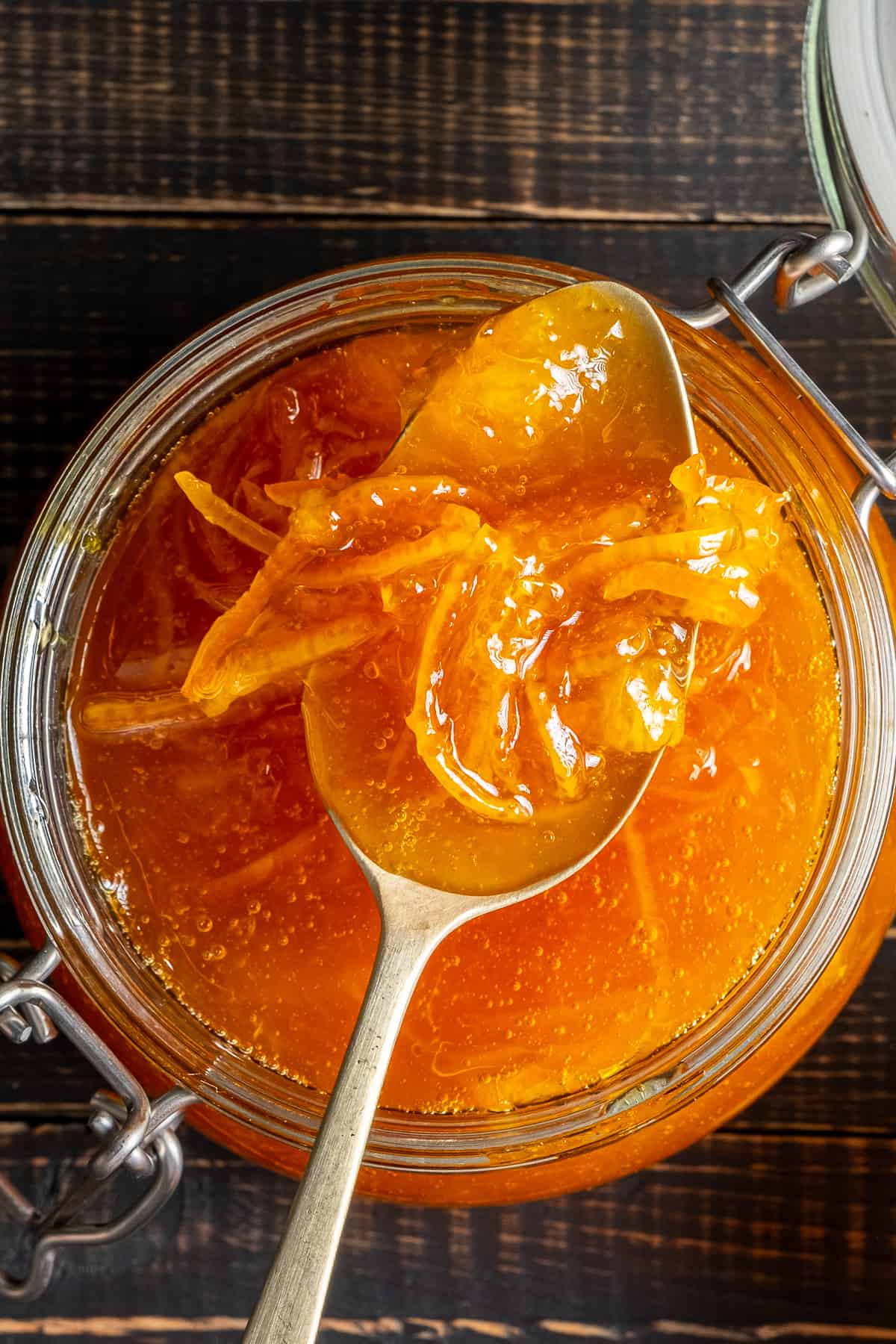Orange jam in a glass jar and a spoon inside.