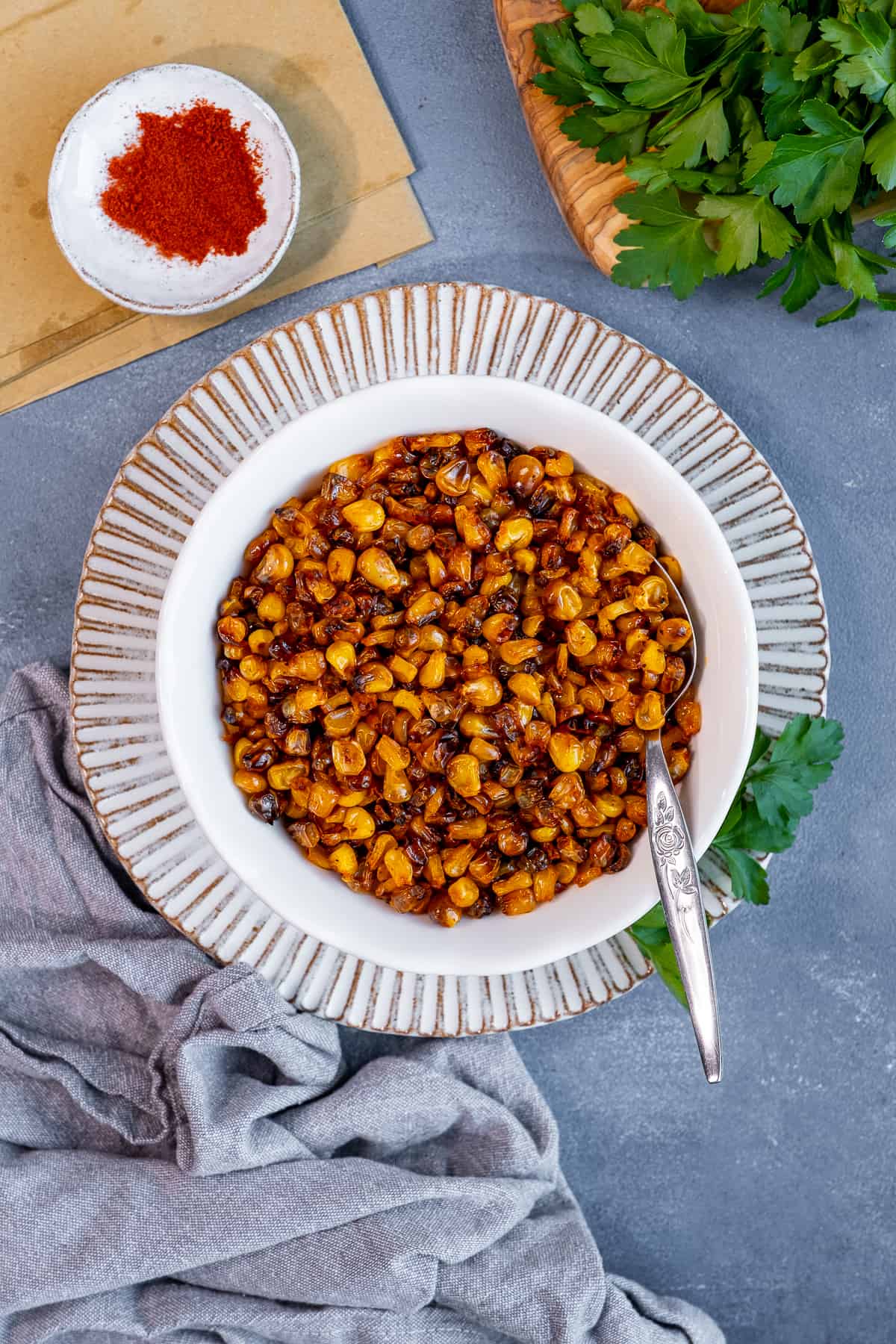 Roasted corn kernels in a white bowl photographed from top view.