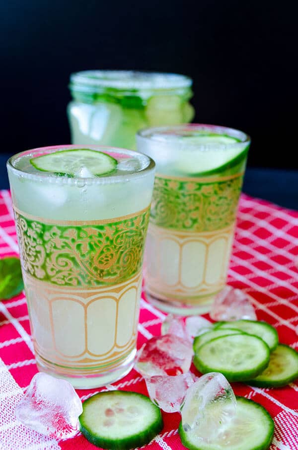 Nothing can beat the heat better than a big glass of delightful lemonade flavored with cucumber, lemon zest and fresh mint. Don’t forget to add lots of ice cubes into this incredibly Fresh Cucumber Mint Lemonade! #lemonade #cucumberlemonade #cucumbermintlemonade #cocktail Cucumber lemonade recipe picture. Served in small glasses garnished with cucumber slices.